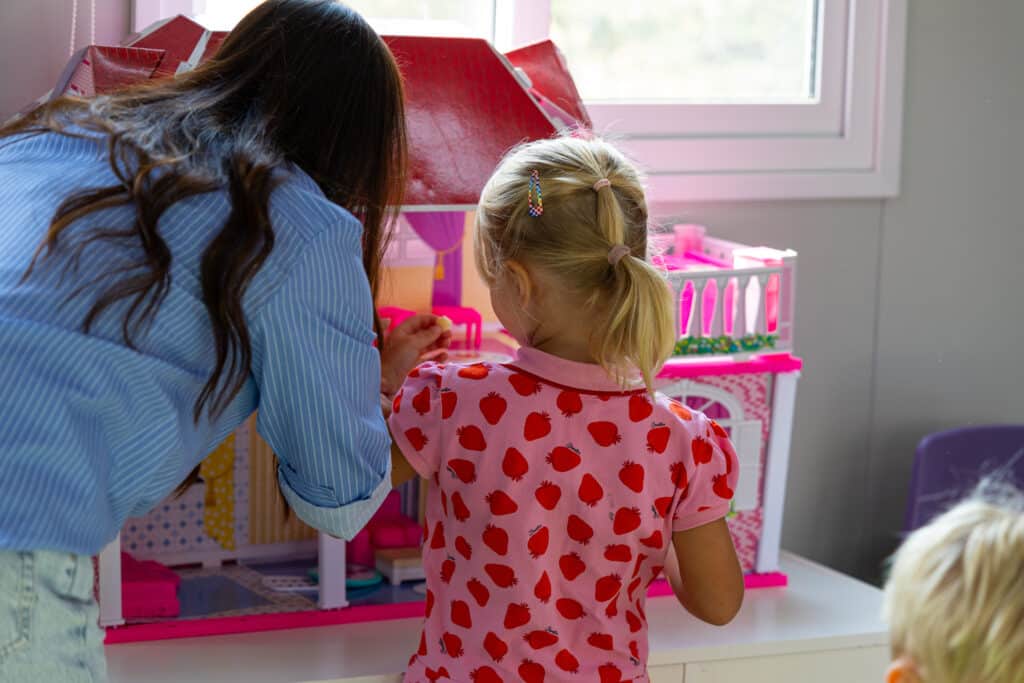 An adult and child exploring a dolls’ house in a Golden Oak classroom.