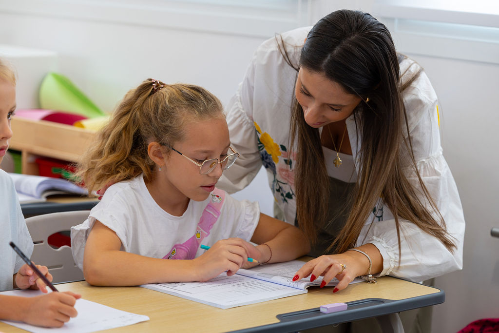 A teacher helping a pupil with classroom work at Golden Oak.