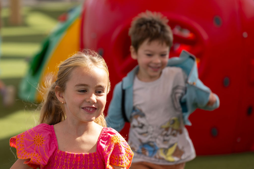 Children playing beside colourful outdoor play equipment at Golden Oak.