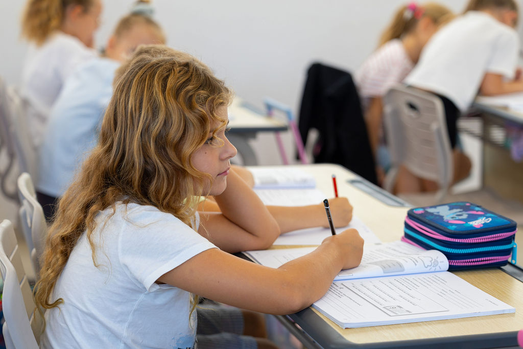 A pupil with a pencil and workbook during a Golden Oak classroom lesson.