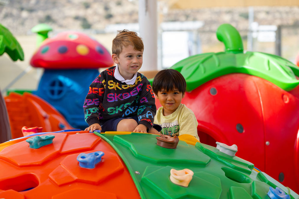 Two children playing with a toy tea set beside colourful playhouses at Golden Oak.
