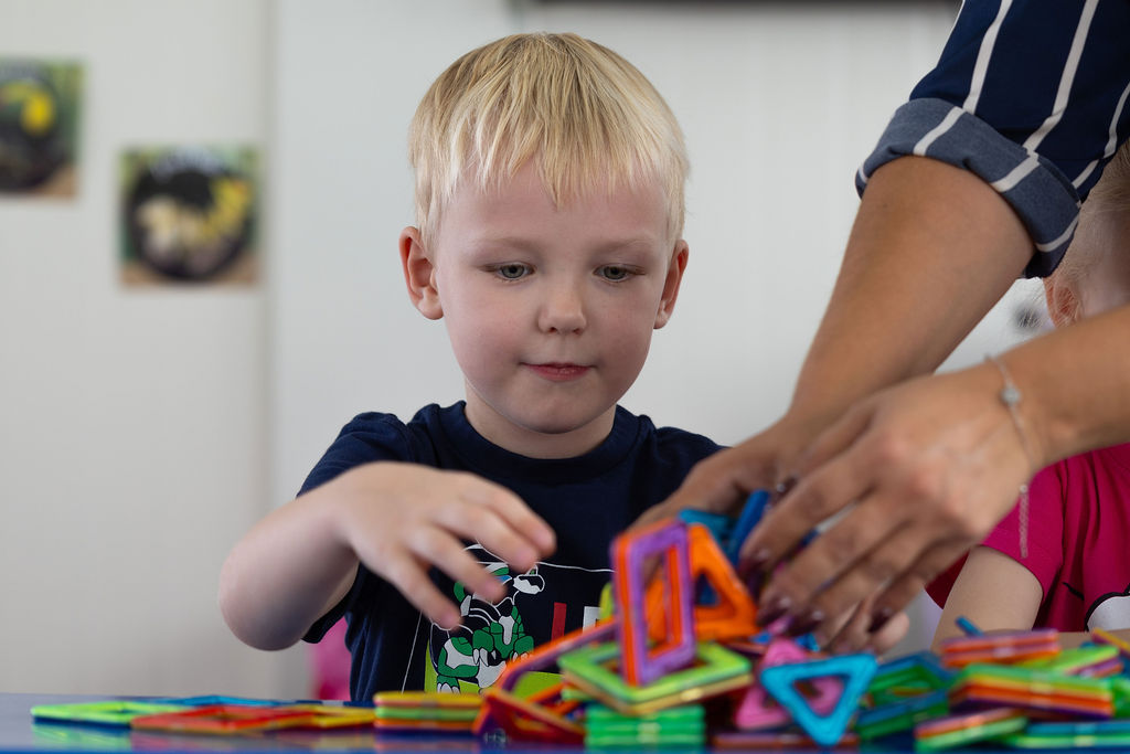 An adult and children exploring magnetic construction pieces at Golden Oak.