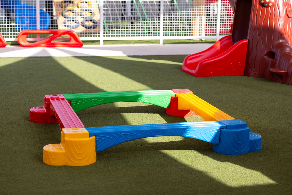 Colourful balance equipment and a slide in Golden Oak's outdoor play area.