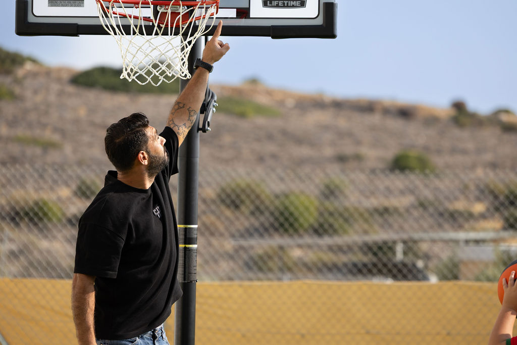 An adult demonstrating a basketball movement on Golden Oak's outdoor court.