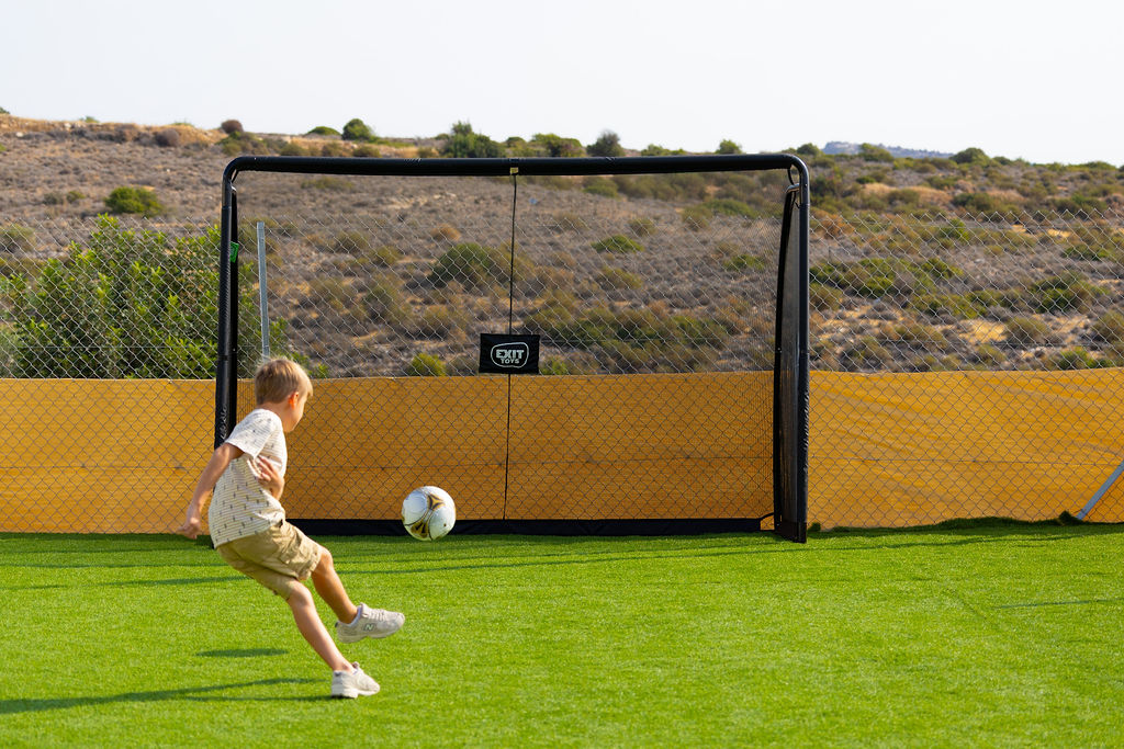 A child playing football on the outdoor sports area at Golden Oak.