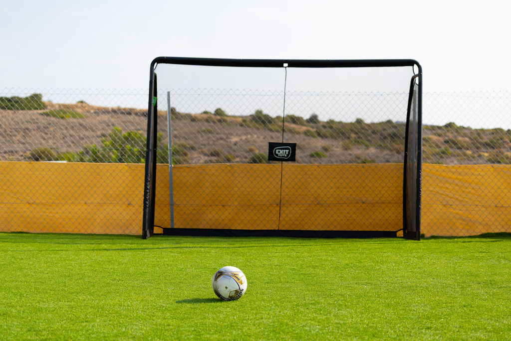 A football on the artificial-turf sports area in front of a goal at Golden Oak.