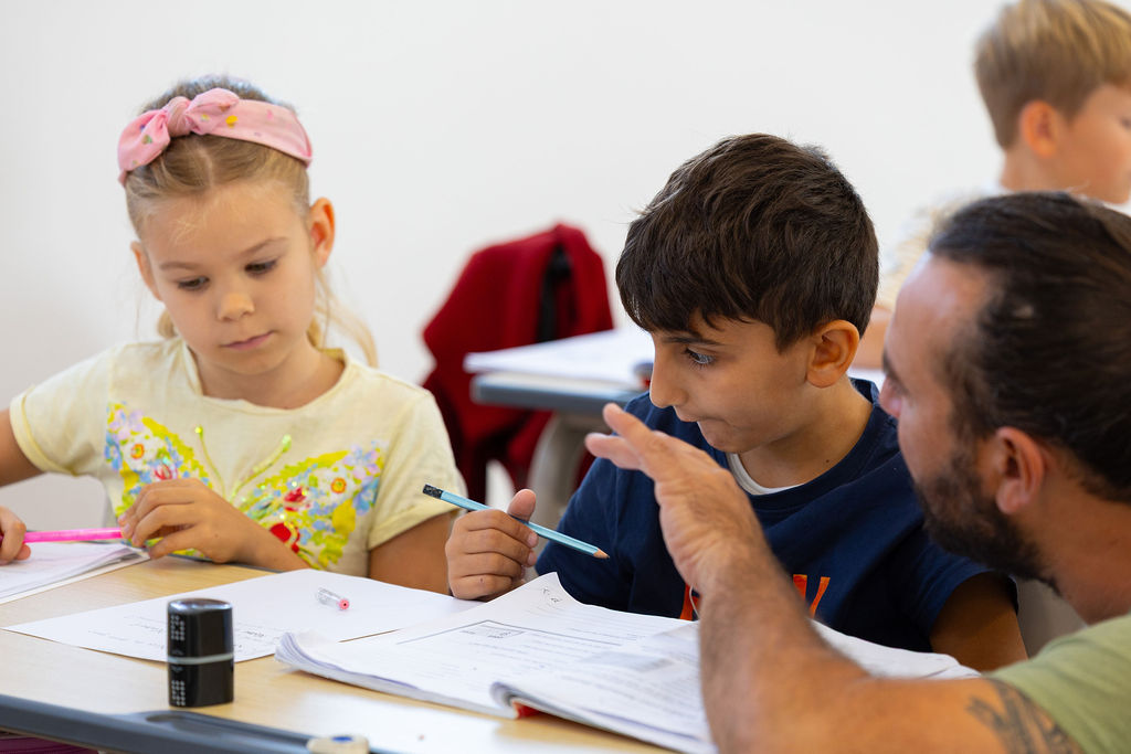 Pupils working around a classroom table with an adult at Golden Oak.