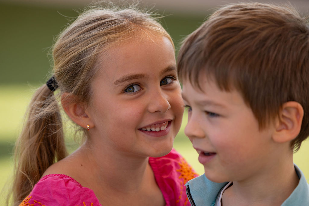 Two children smiling together in Golden Oak's play area.